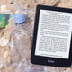 The Kobo Clara 2E sitting on a trash-covered beach.